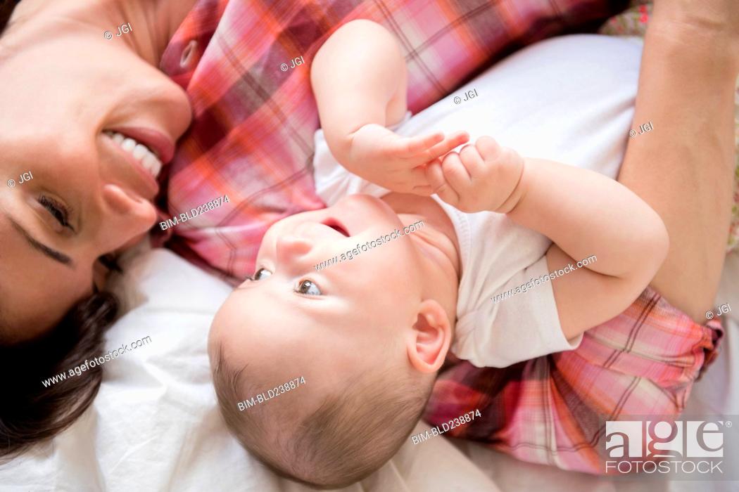 Stock Photo: Caucasian mother laying on bed holding baby daughter.