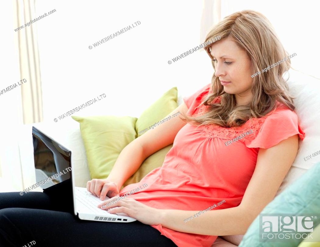 Stock Photo: Concentrated woman using a laptop sitting on a sofa in the living-room.