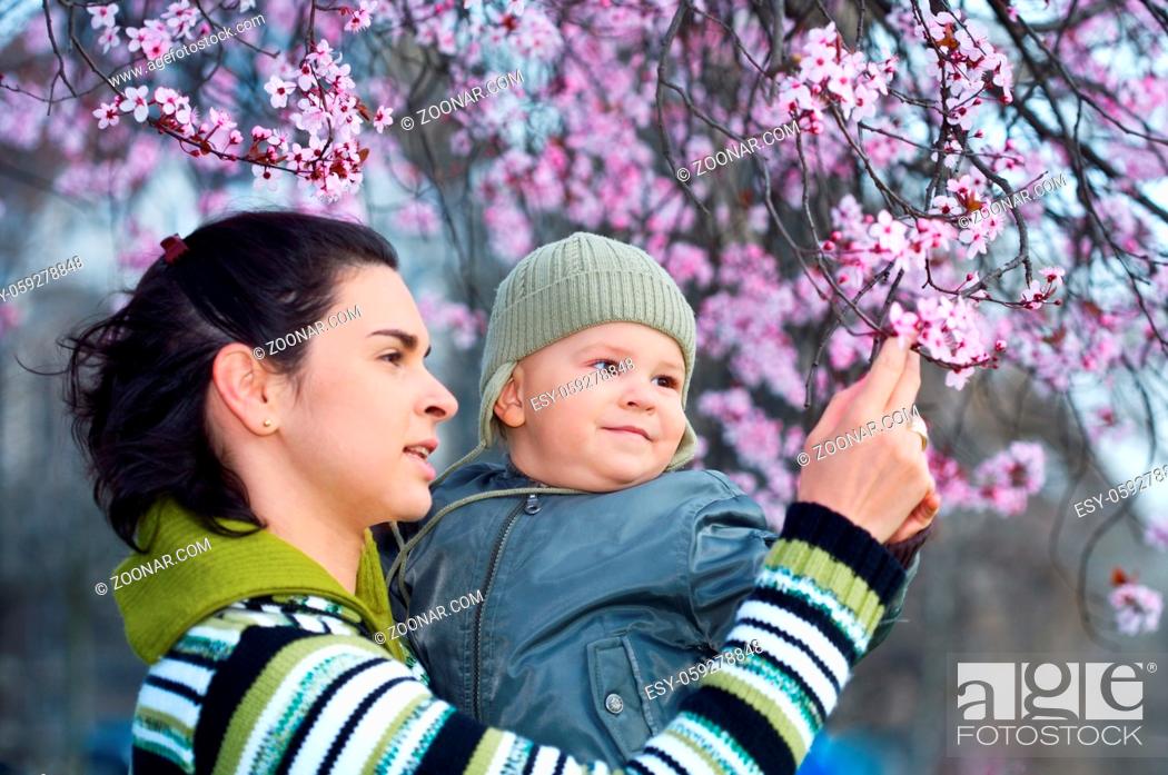 Stock Photo: Mother and her 2 years old child enjoy the early spring between flowers.