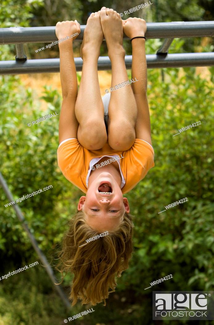 Stock Photo: Girl hanging upside down from a jungle gym.