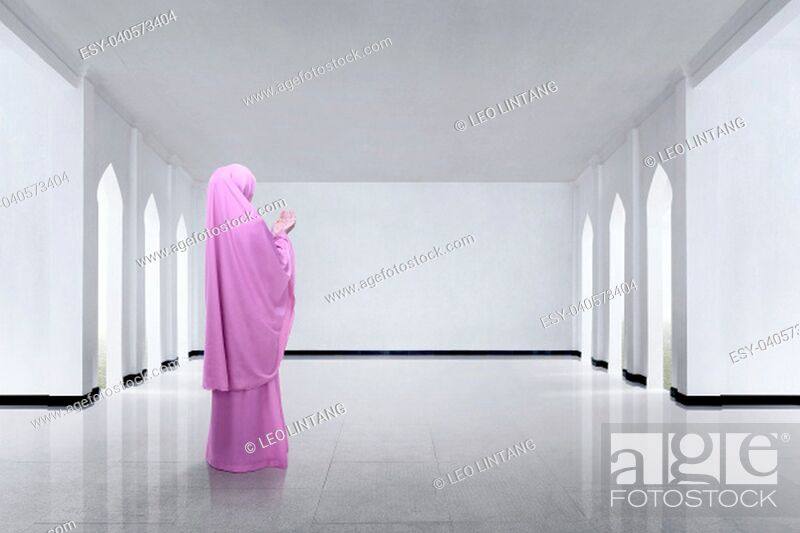 Imagen: Back view of asian muslim woman raising hand and praying on the mosque.