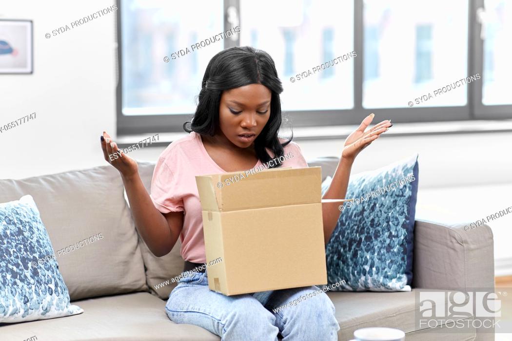 Stock Photo: sad african american woman with parcel box at home.