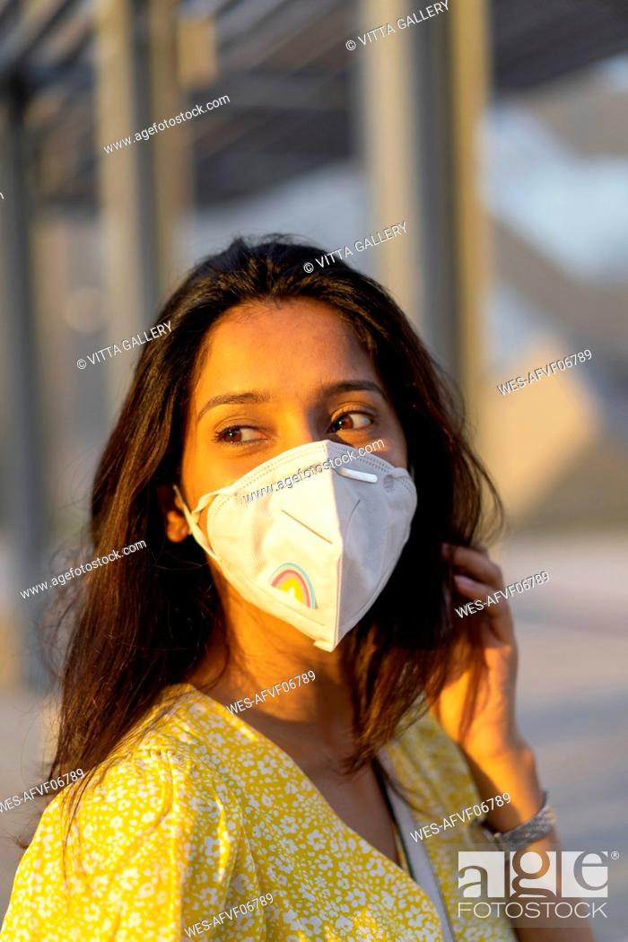 Stock Photo: Thoughtful young woman wearing face mask in city.