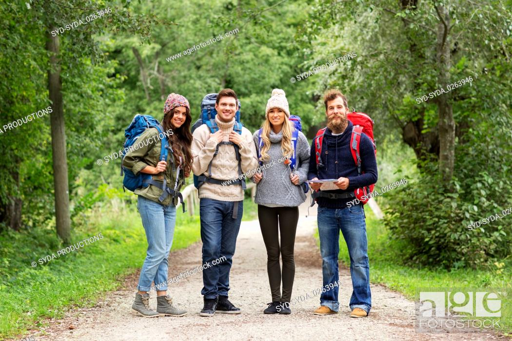 Stock Photo: friends or travelers hiking with backpacks and map.