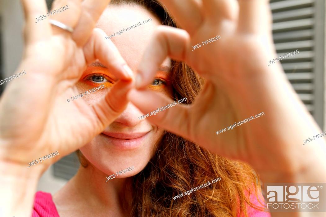 Stock Photo: Smiling woman looking through binoculars made from fingers.