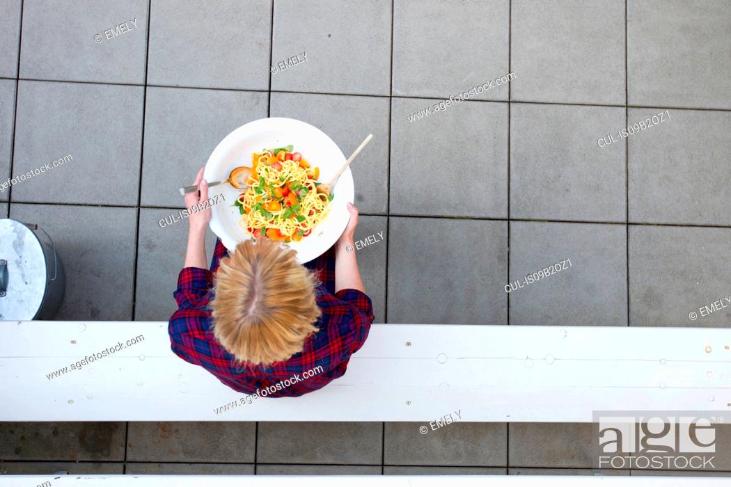 Stock Photo: Overhead view of woman holding serving bowl of pasta.