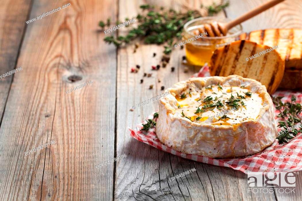 Stock Photo: A real Camembert from France with thyme, honey and toasted bread on old wooden rustic table. Soft cheese on a wooden background with copy space.