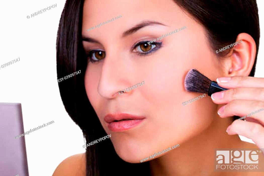 Stock Photo: Beautiful woman applying blusher or foundation to contour and smooth the skin of her cheek with a soft small cosmetics brush.