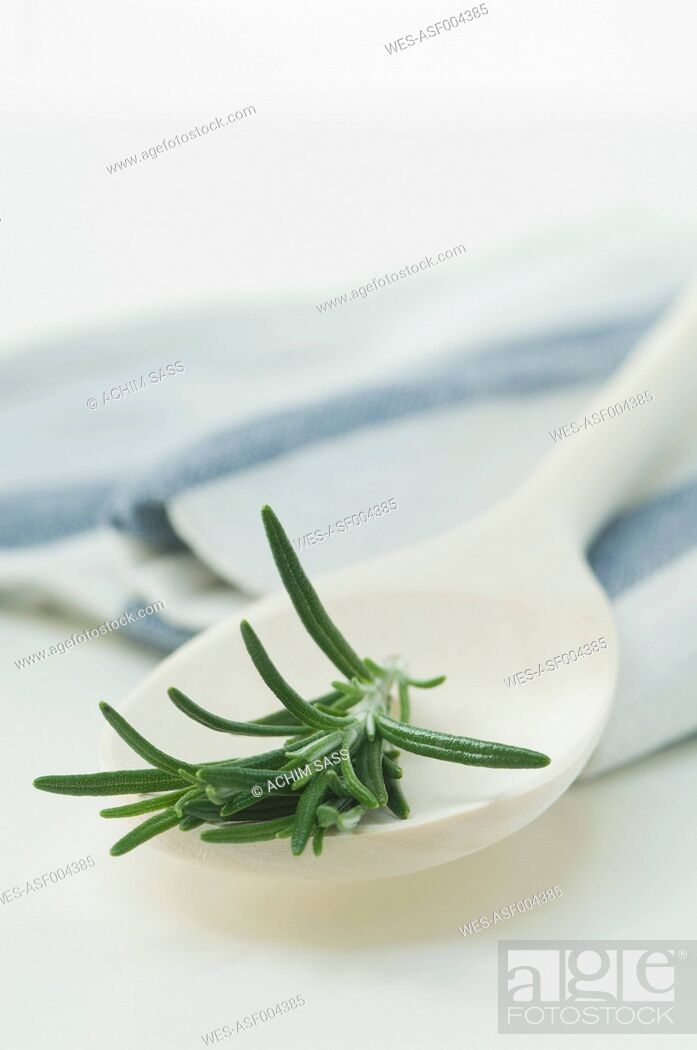 Stock Photo: Wooden spoon with rosemary on white background, close up.