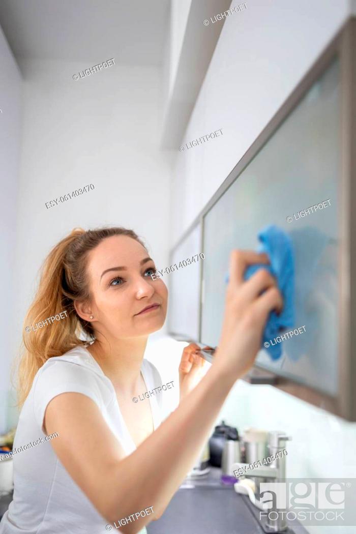 Stock Photo: Young woman polishes a modern bright kitchen.