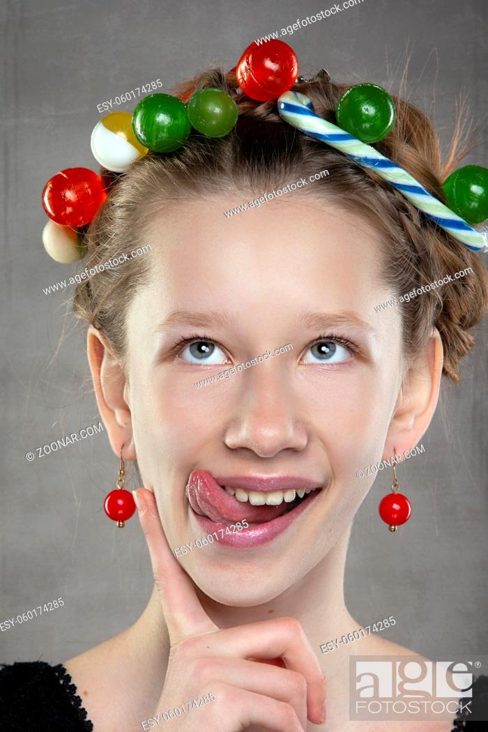 Stock Photo: A funny teenager girl with a wreath of sweets on her head shows her tongue.