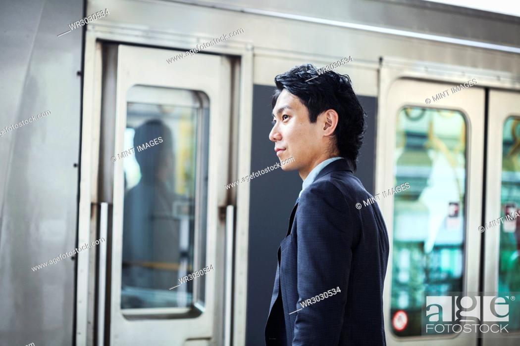 Stock Photo: Businessman wearing suit standing at train station platform.