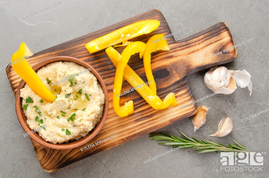 Stock Photo: Flat lay view at vegetable Hummus dip dish topped with olive oil served with yellow sweet bell pepper slices.
