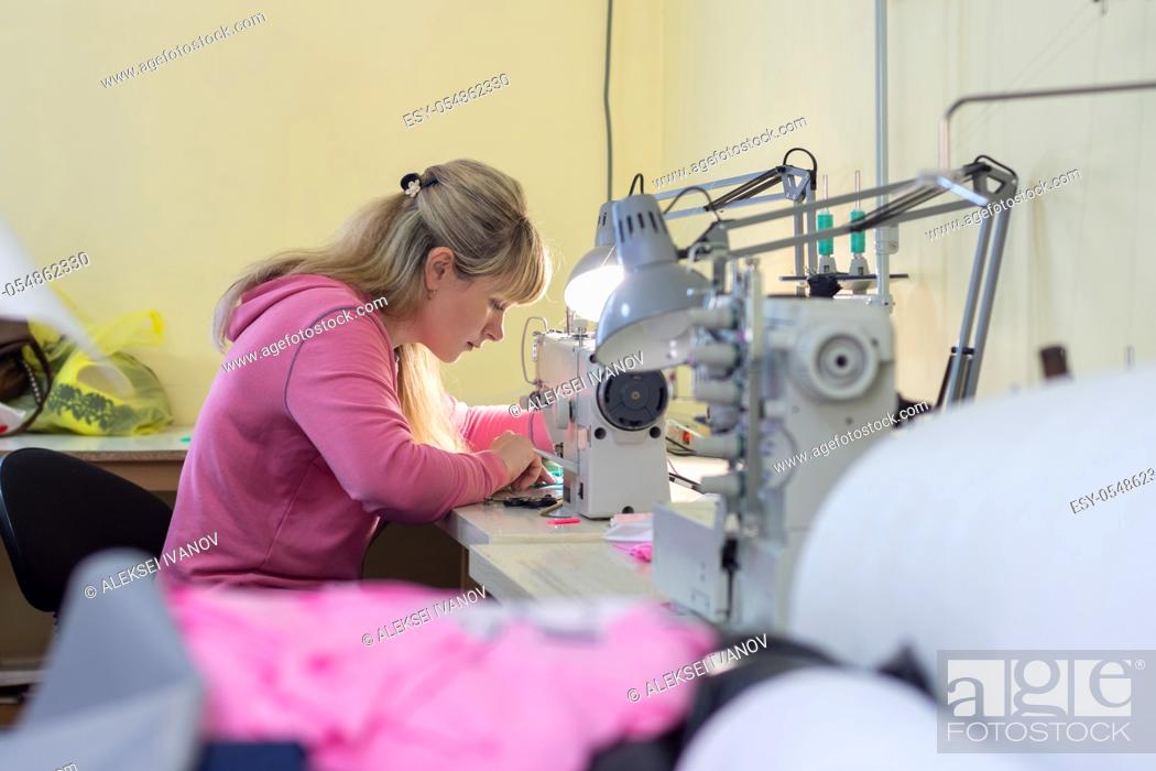 Stock Photo: Worker in sewing workshop sews on a professional sewing machine.