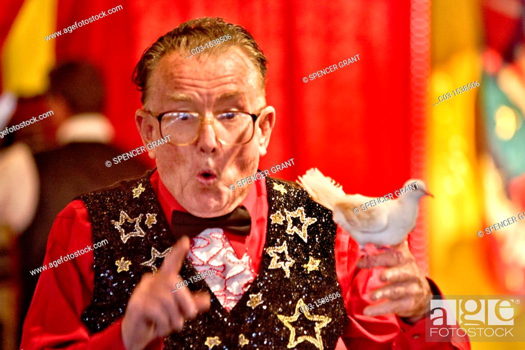 Stock Photo: An elderly magician performs a 'disappearing dove' act in the amusement park the Orange County Fair in Costa Mesa, CA.