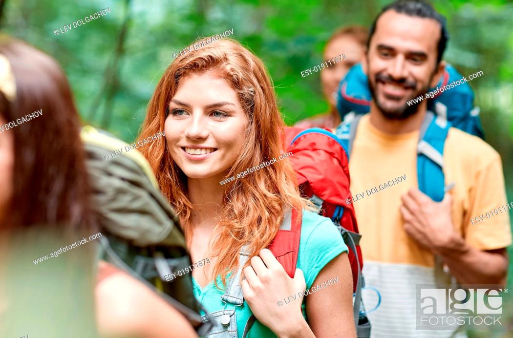 Stock Photo: adventure, travel, tourism, hike and people concept - group of smiling friends walking with backpacks in woods.