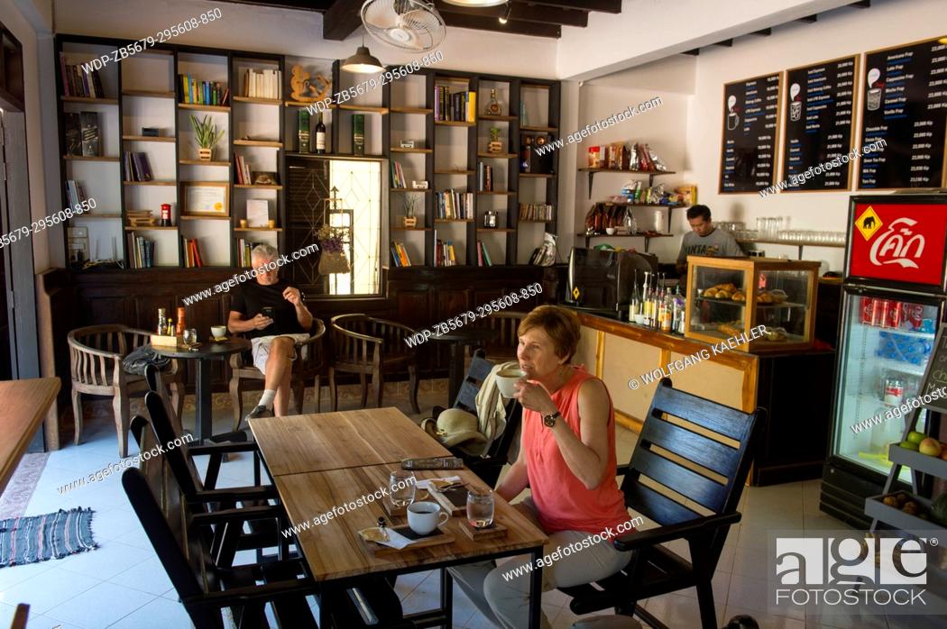 Stock Photo: A tourist (Model Release 20020923-10) is enjoying coffee in one of the numerous coffee houses in the UNESCO world heritage town of Luang Prabang in Central Laos.