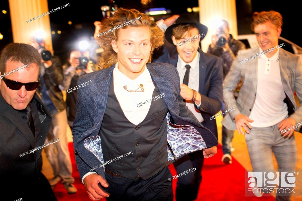 Stock Photo: Enthusiastic celebrities arriving and running from paparazzi at red carpet event.