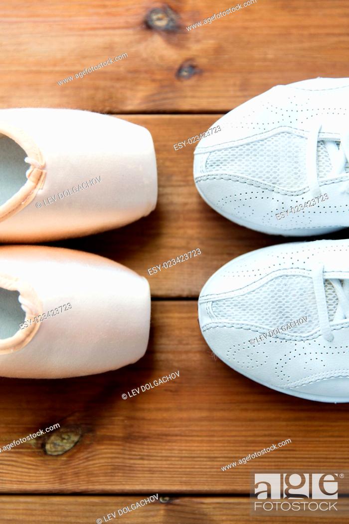 Stock Photo: sport, ballet, fitness, footwear and objects concept - close up of sneakers and pointe shoes on wooden floor.