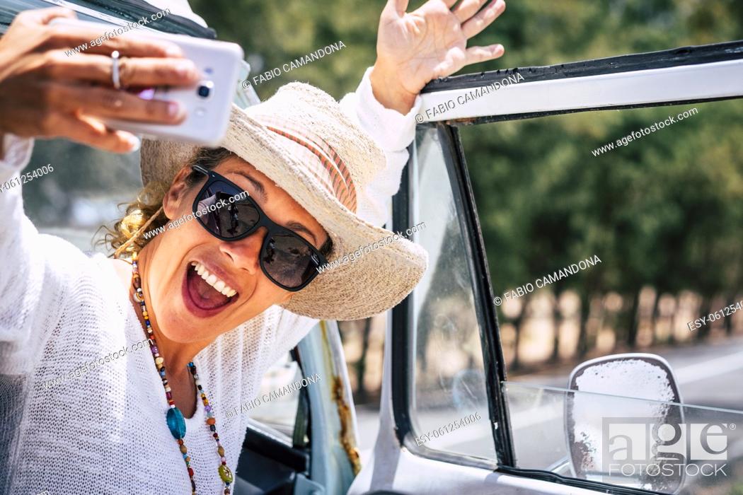 Photo de stock: Overjoyed and excited young woman taking selfie picture with mobile smartphone. Female people use cellular during travel.