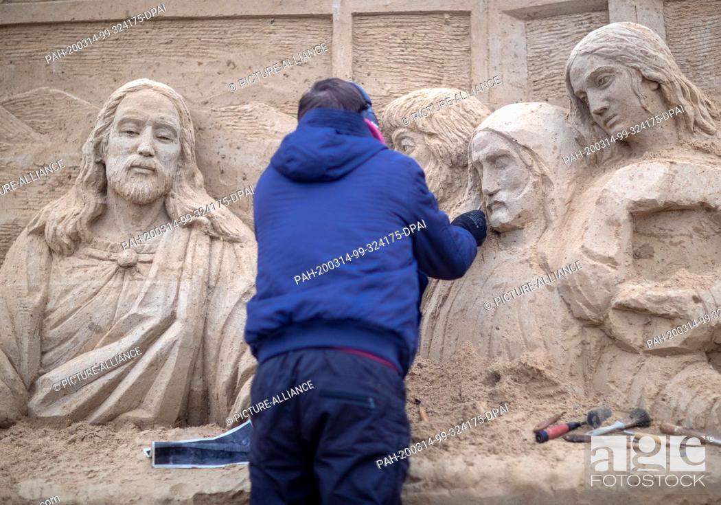 Stock Photo: 10 March 2020, Mecklenburg-Western Pomerania, Binz: A sand artist works on a sand painting with the scene of the Last Supper at the sand sculpture festival.