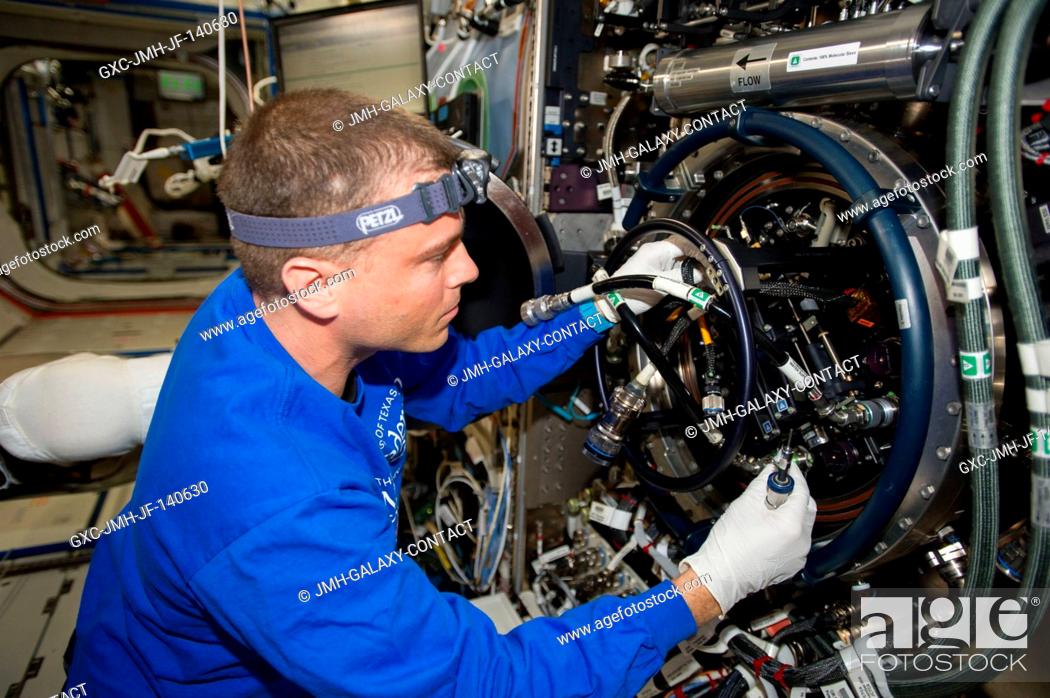 Stock Photo: NASA astronaut Reid Wiseman, Expedition 40 flight engineer, performs routine in-flight maintenance on the Multi-user Drop Combustion Apparatus (MDCA) inside the.