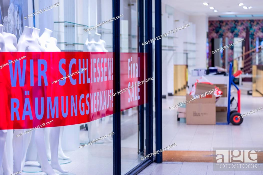 Stock Photo: 21 December 2020, North Rhine-Westphalia, Münster: ""We're closing - clearance sale!"" is written in an empty shop window on Prinzipalmarkt.