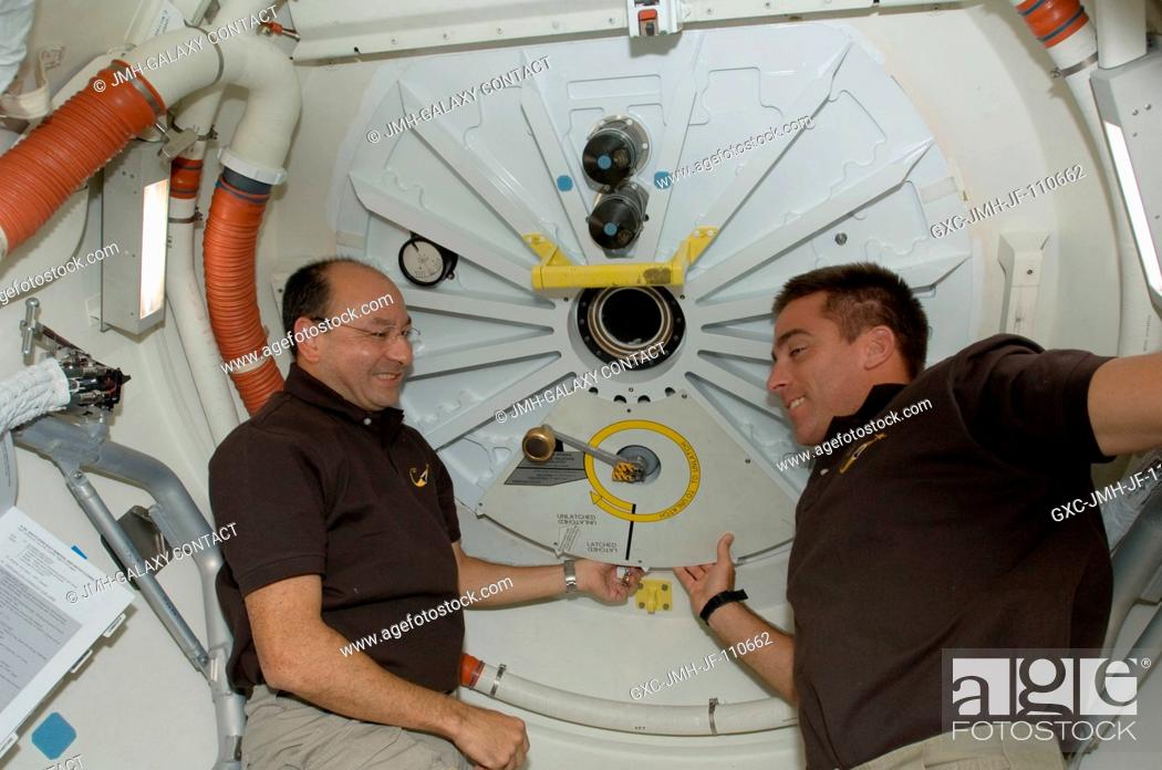 Stock Photo: Astronauts Mark Polansky (left), STS-127 commander; and Christopher Cassidy, mission specialist, close the hatch on the middeck of Space Shuttle Endeavour prior.