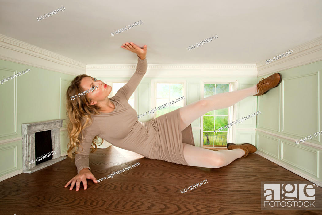 Stock Photo: Giant young woman trapped in small room.