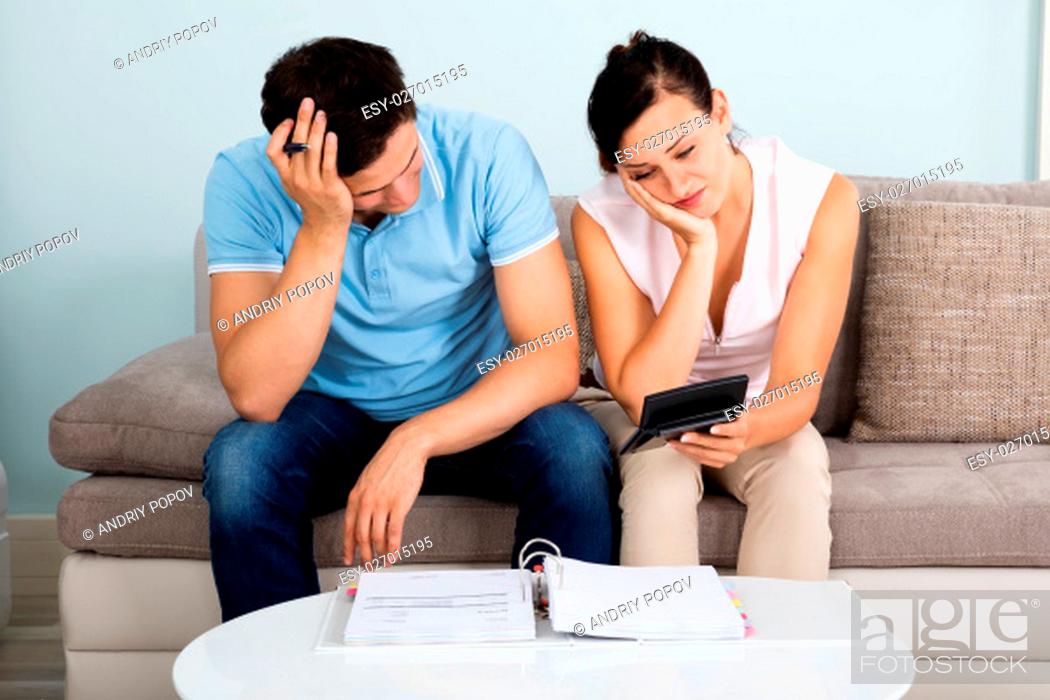 Stock Photo: Young Unhappy Couple Calculating Bills At Home.