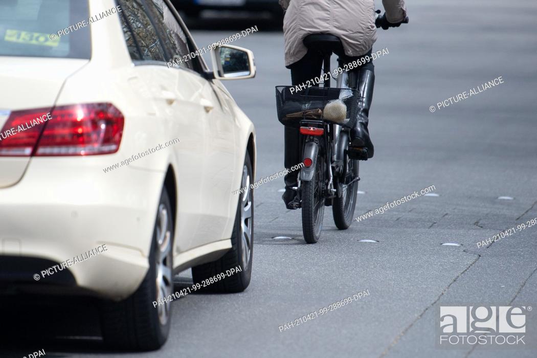 Stock Photo: 13 April 2021, Rhineland-Palatinate, Mainz: A car drives close behind a cyclist. The trend towards bicycles and e-bikes, which grew significantly during the.