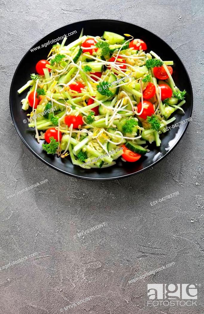 Stock Photo: orzo pasta salad with cucumber slices, celery sticks, tomato and bean sprouts on black plate on concrete background, healthy life concept.