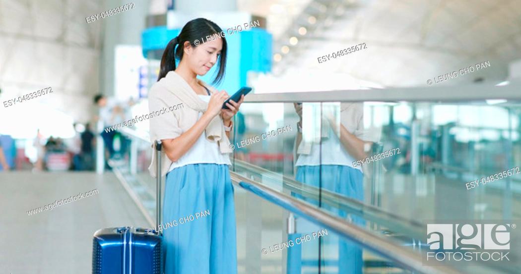 Stock Photo: Woman checking flight number on cellphone in the airport.