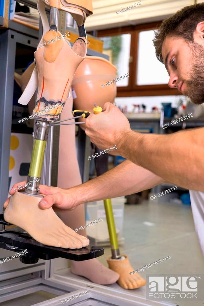 Stock Photo: Close up on single adult technician using special tool to adjust length on prosthetic false limb assembly in workshop.