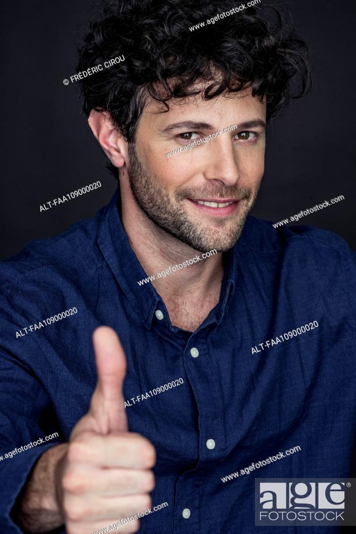 Photo de stock: Man giving thumbs up and smiling, portrait.