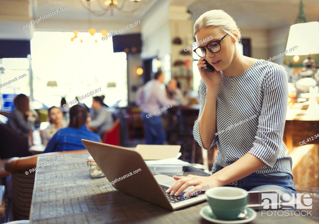 Stock Photo: Creative businesswoman talking on cell phone and using laptop in cafe.