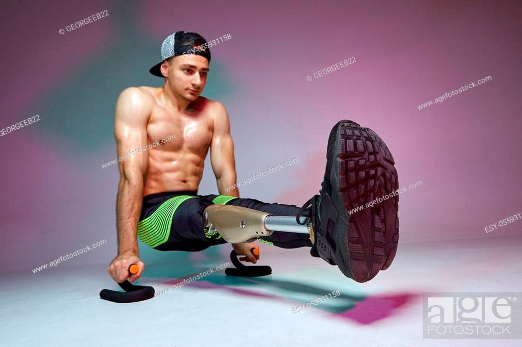 Stock Photo: A young muscular man with a disability with a prosthetic leg is training in a gym. Motivation workout poster.