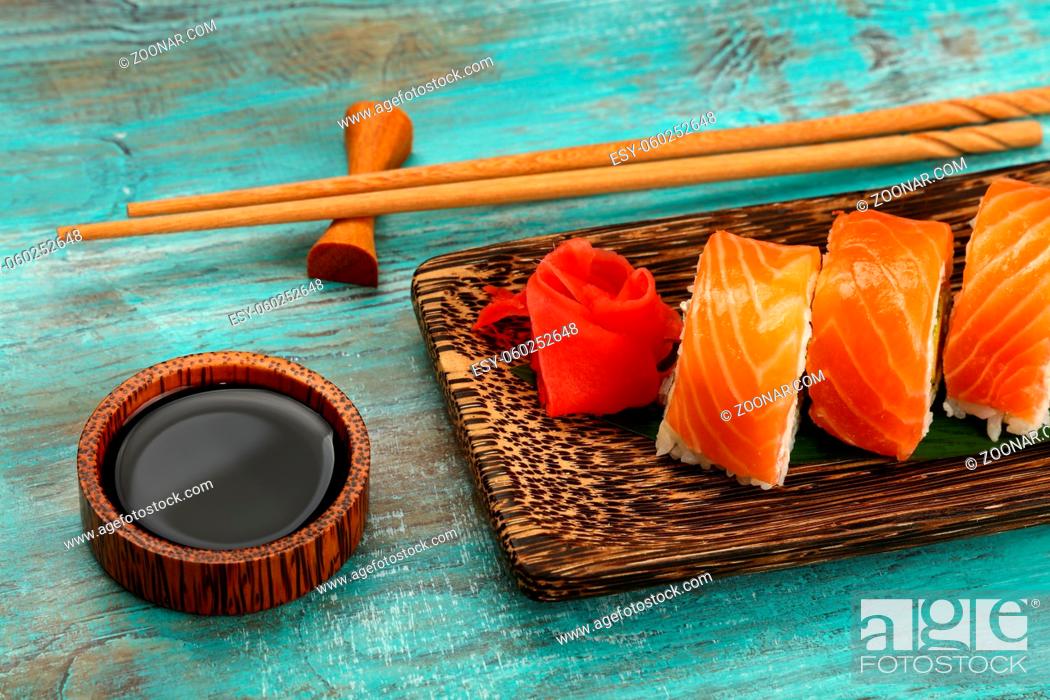 Stock Photo: Close up one set of six Philadelphia sushi rolls with raw salmon served on palm wood plate on blue table, higgh angle view.