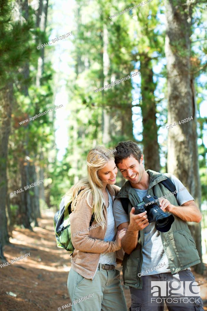 Stock Photo: Smiling couple looking at digital camera in woods.