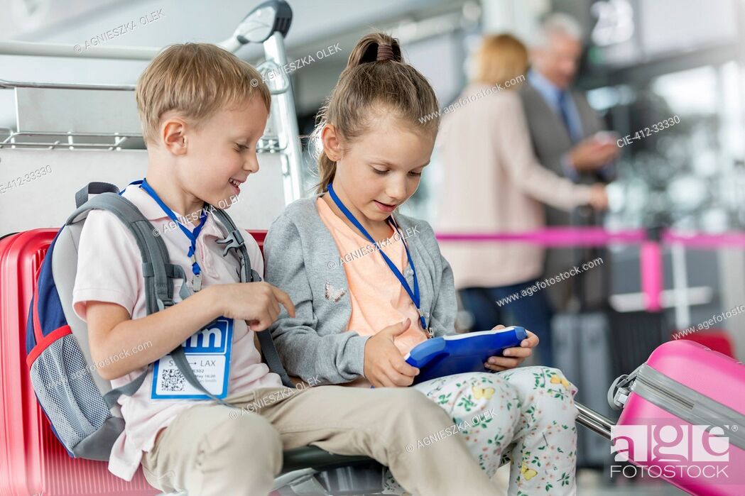 Stock Photo: Brother and sister using digital tablet in airport departure area.