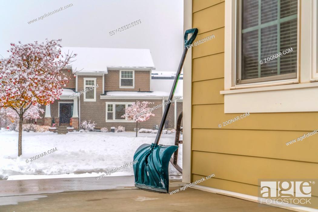 Stock Photo: Snow shovel against snow covered landscape in Utah. The snow pusher is leaning on the wall of a home in Daybreak, Utah.