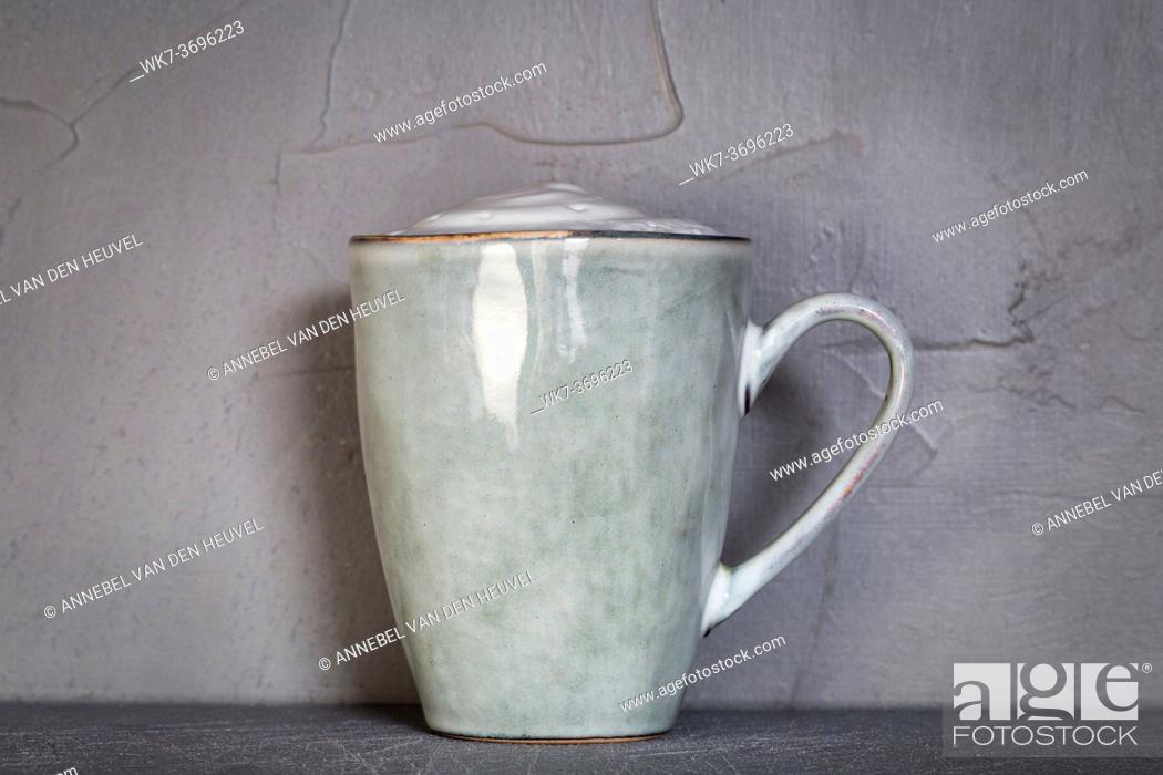 Stock Photo: Ceramic mug with white foam gray natural stone design with concrete wall background, coffee or tea concept, copy space close up.