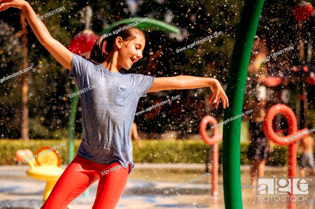 Stock Photo: Little girl play with splashes on water playground in summer park. Child leisures in aquapark, aquatic adventure, female kid having fun in fountain, waterpark.