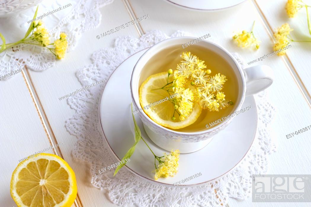 Stock Photo: A cup of herbal tea with linden flowers on a white table.