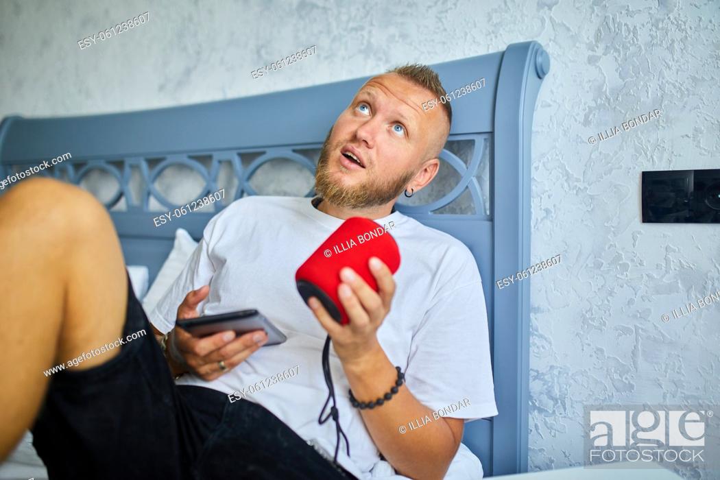 Stock Photo: Male testing talking smart wireless speaker, man controlling home devices with a voice commands, sitting on sofa at home, Concept of smart home.