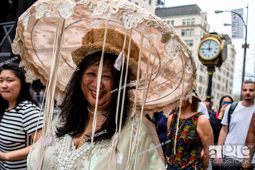 Stock Photo: New York, NY - April 16, 2017. A woman in a large and elaborate hat bedecked in lace and with festoons of ribbons at New York's annual Easter Bonnet Parade and.