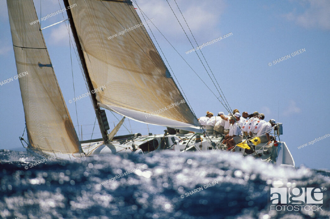 Imagen: Hawaii, Kenwood Cup, Wave in foreground of crew sitting on yacht starboard side.