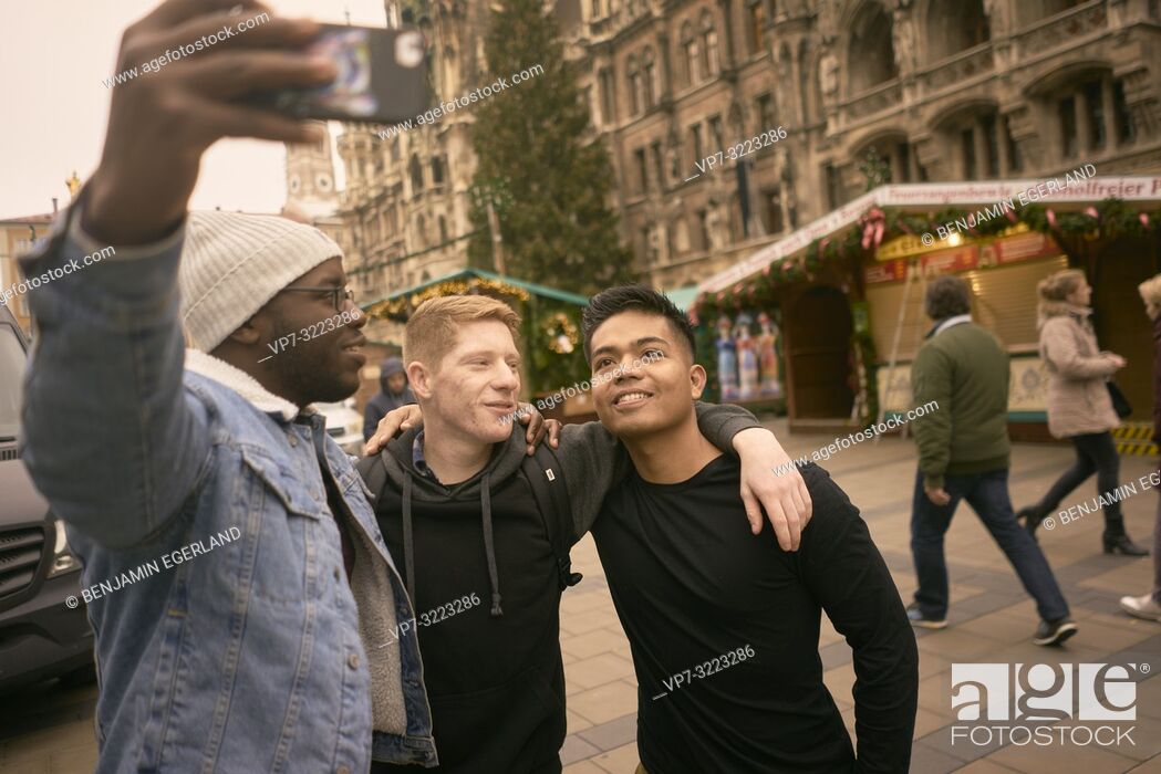 Stock Photo: young men taking selfie in front of Neues Rathaus and Christmas market at Marienplatz in Munich, Germany.
