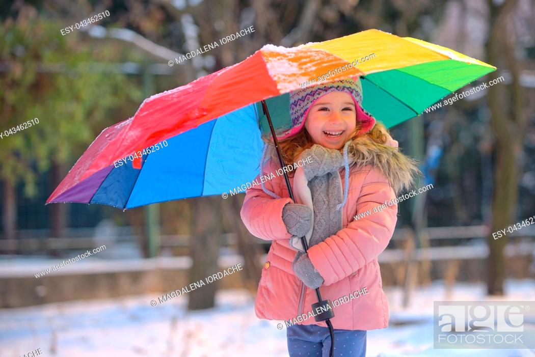Stock Photo: Little girl under umbrella in snowy winter.