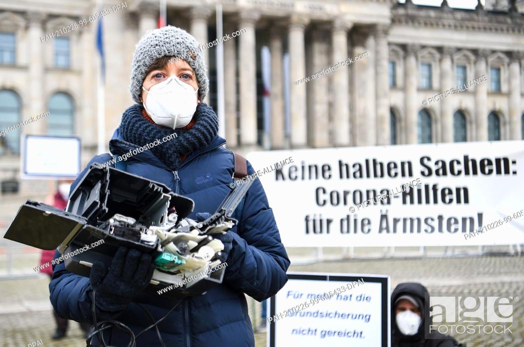 Stock Photo: 26 February 2021, Berlin: A demonstrator with mouth-nose covering holds half a printer in her hand. In front of the German Bundestag people of the action ""No.